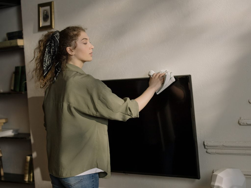 woman cleaning mounted tv